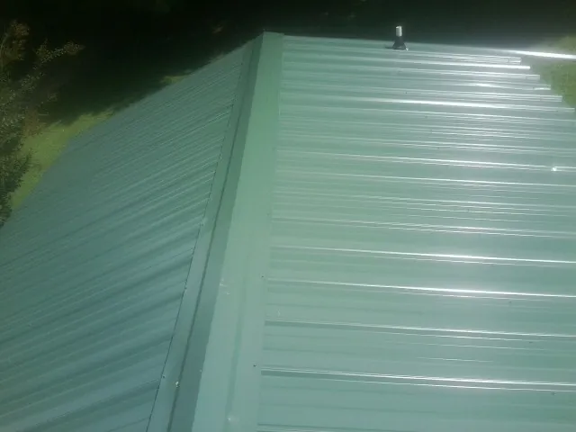 New green metal panels meeting at the ridge of a roof — Flat Roof Repair work by our crew in Silver Plume