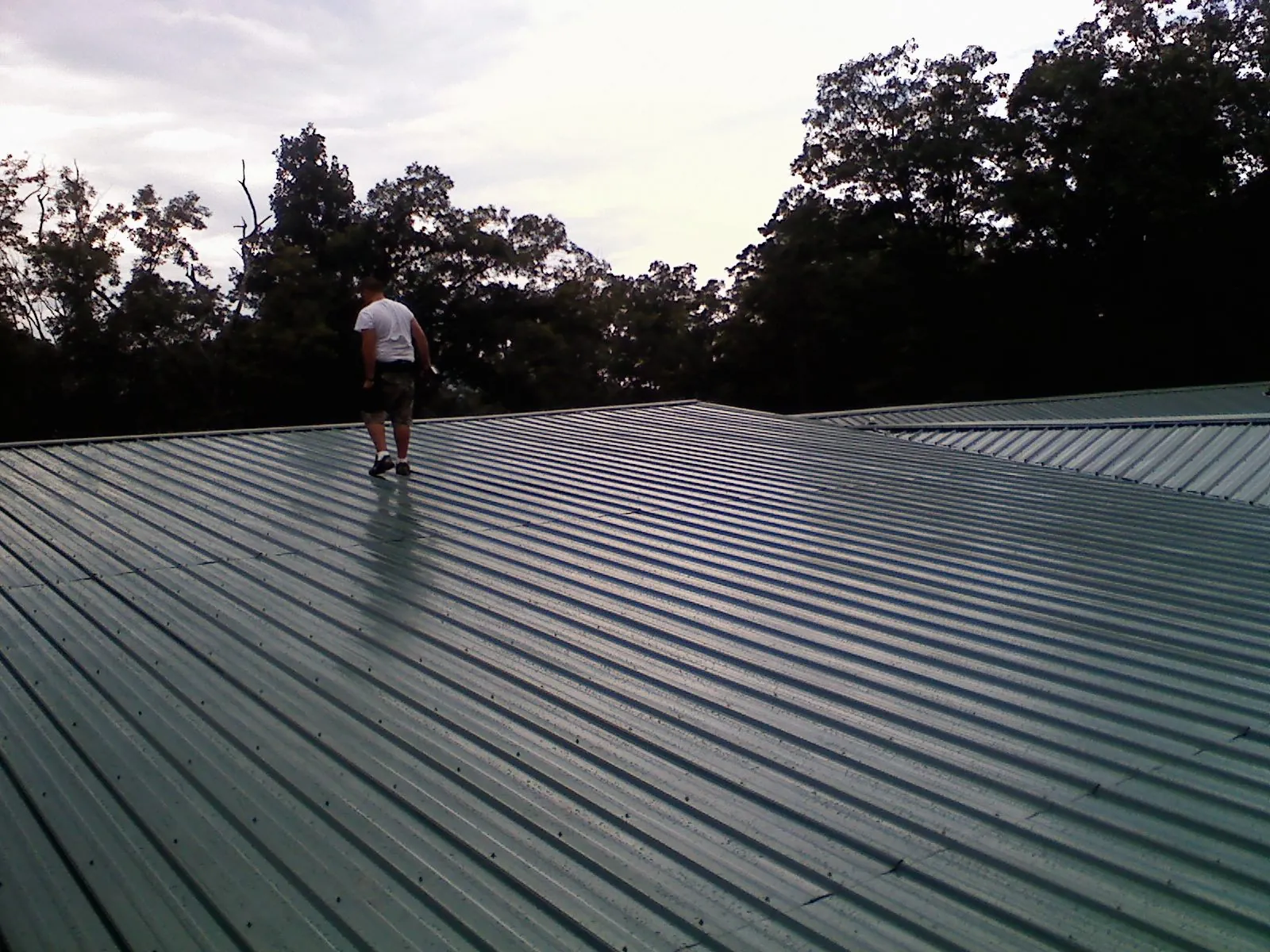 Roofer walking a wide expanse of new green metal roofing in Silver Plume