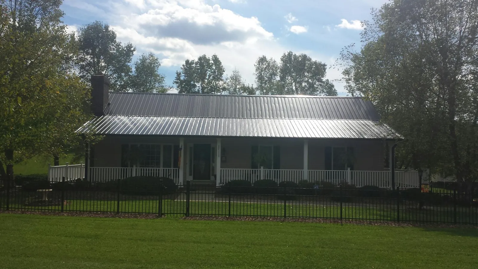 Gray metal roof on a brick ranch with a full width front porch — Gutter Guard Installation work by our crew in Silver Plume