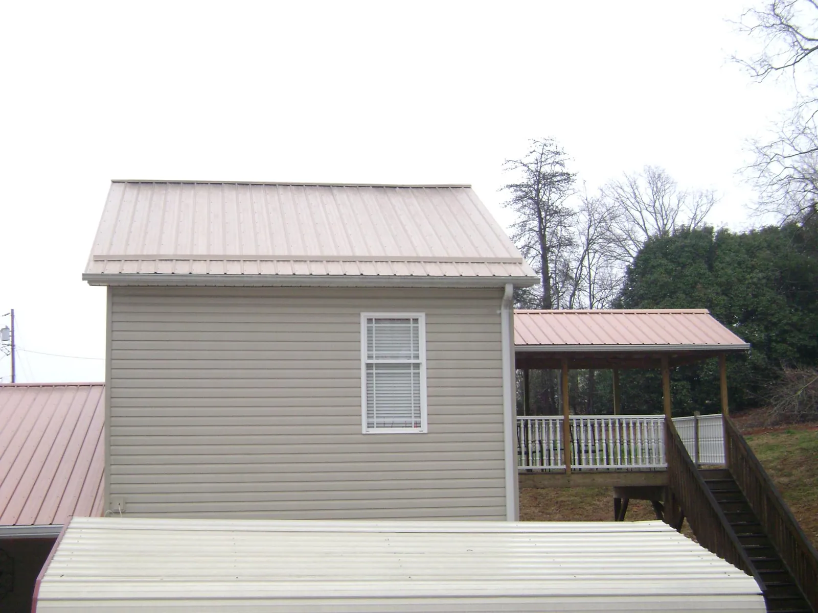 Tan metal roofs on a two story addition and attached porch, from a Roof Replacement job in Silver Plume